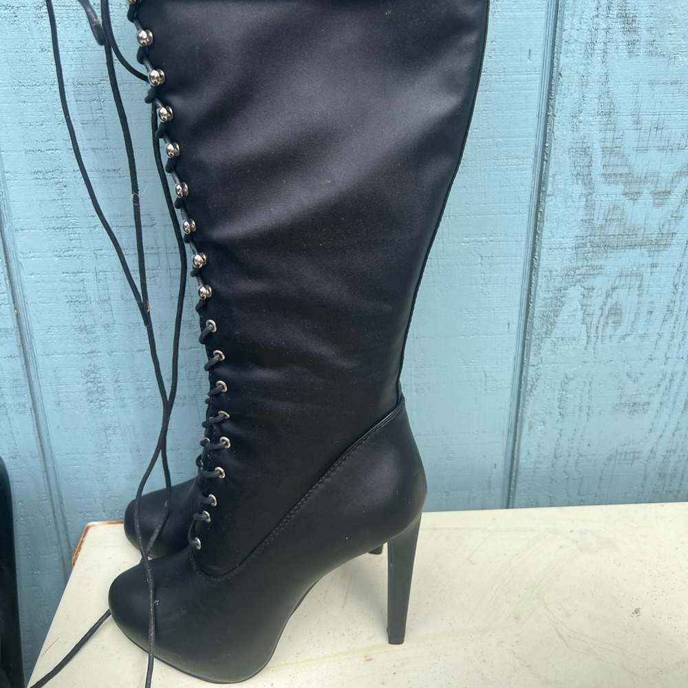 Knee-high, lace-up, heeled black boots.
